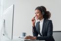 close up call center operator in wireless headset talking with customer, woman in headphones with microphone consulting client on phone in customer support service, looking at computer screen..